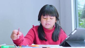 Asian girl sitting at home coloring pictures. video