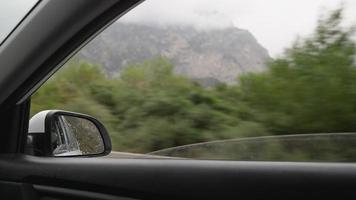 Blick aus dem Inneren eines fahrenden Autos entlang der Autobahn auf den Seitenspiegel bei Regen. das Konzept von Fahrzeugen und Fahrern. keine Leute. video