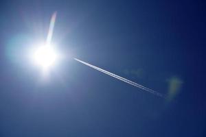 Airplane trails tracks chemtrails in the deep blue sky photo