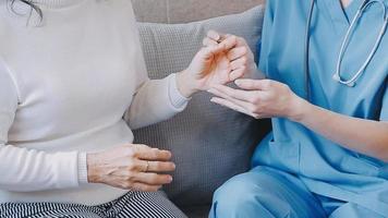 Homecare nursing service and elderly people cardiology healthcare. Close up of young hispanic female doctor nurse check mature caucasian man patient heartbeat using stethoscope during visit video