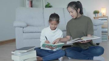 Mother teaching lesson for daughter. Asian young little girl learn at home. Do homework with kind mother help, encourage for exam. Asia girl happy Homeschool. Mom advise education together. video