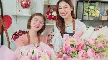 Portrait of Two young beautiful women florist partners giving floral bunch, smiling and looking at camera, lovely business entrepreneur, flower shop happy work, brightly colorful flora bouquet store. video