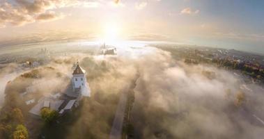 circular rotation and aerial panoramic view overlooking the old city and historic buildings of medieval castle near wide river in early morning with fog and mist video