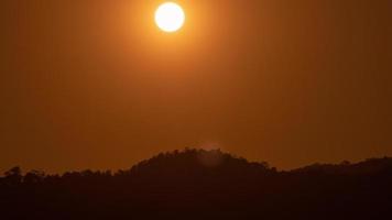 pôr do sol sobre uma montanha no céu laranja 4k vídeo lapso de tempo. video