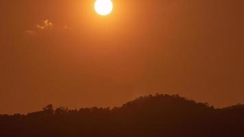 puesta de sol sobre una montaña en el cielo naranja 4k video de lapso de tiempo.