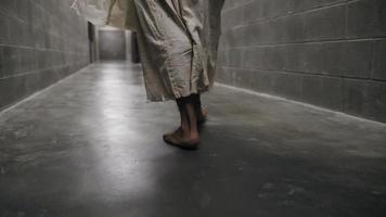 Füße eines Mannes in weißem Gewand, der im Gefängnisflur spazieren geht video