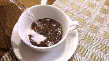 scrosciante caldo bollente acqua in un' bianca tazza contenente fermentato caffè e zucchero. video