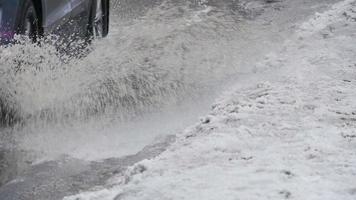 spray de debajo de las ruedas de un coche que pasa, charcos de primavera, cámara lenta video