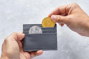 Man holding bitcoin coins. Businessman puts bitcoin coins in a wallet. The concept of buying bitcoins. Bitcoin and wallet. Preservation. Cryptocurrency. virtual money photo