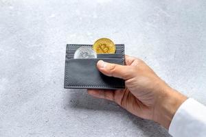 Metal bitcoins in a gray leather wallet. Bitcoin - a modern virtual form of money photo