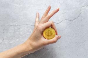 mano femenina sostiene bitcoin y criptomoneda. concepto de blockchain e inversión de dinero foto