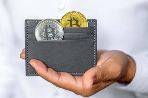 Gold and silver bitcoin coin is invested in a wallet. The concept of buying bitcoins. Bitcoin and wallet. Saving bitcoins. Cryptocurrency. Close-up. photo