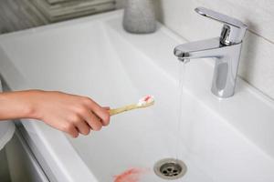 sangre en el cepillo de dientes en el fondo del lavabo. enfoque selectivo en el cepillo de dientes. foto