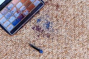 Eye shadow fell and scattered on carpet. Top view. photo
