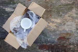 Packed cup in a plastic bubble wrap on an old wooden background. Fragile package. photo