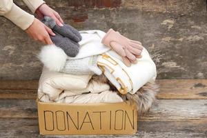 Donation box with winter clothes on an old wooden background. photo