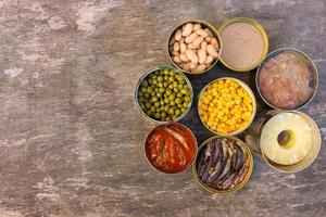 Different open canned food on old wooden background. Top view. Flat lay. photo