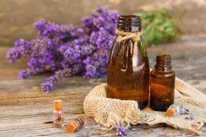 aceite de lavanda en diferentes botellas sobre fondo de madera. foto