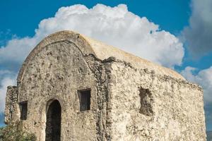 An abandoned Greek chapel against a blue sky with clouds is located on a mountain in an abandoned ghost town near Fethiye in Turkey. Site of the ancient Greek city of Karmilissos from the 18th century photo