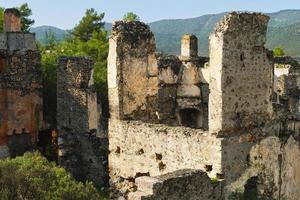 ruinas de la ciudad griega abandonada de levissi cerca del pueblo de kayakoy en fethiye turquía, contra el telón de fondo de las nubes cúmulos, la tragedia de las guerras. sitio de la antigua ciudad de karmilissos foto