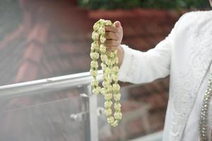 A Groom Holding Jasmine and Magnolia Flowers Necklace photo
