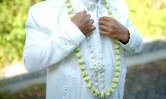 Groom Holding Jasmine and Magnolia Flower Necklace photo