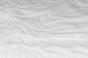 White crumpled or wrinkled bedding sheet or blanket with pattern after guest's use taken in hotel, resort room with copy space, Untidy blanket background texture photo