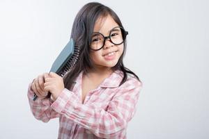 Little girl Asia combing her hair, white background photo