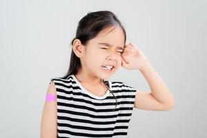 Asian little girl cry with bandage after virus vaccine Kid and child vaccination campaign. Protect your kid with vaccine concept photo