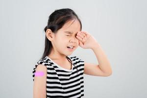 Asian little girl cry with bandage after virus vaccine Kid and child vaccination campaign. Protect your kid with vaccine concept photo