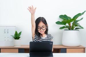 Asian child girl student wow excited on video call learning to studying online class or person learn from home school with tablet photo