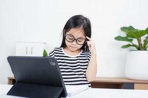 niña estudiante asiática guau emocionada en videollamada aprendiendo a estudiar clase en línea o persona aprende de la escuela en casa con tableta foto