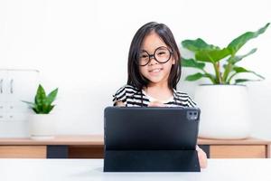 niña estudiante asiática guau emocionada en videollamada aprendiendo a estudiar clase en línea o persona aprende de la escuela en casa con tableta foto