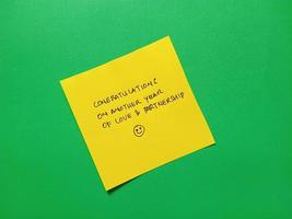 greeting text written on yellow memo stick and isolated on green background photo