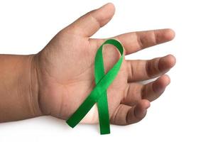 Green ribbon in hand.treatment concept for ovarian cancer and cervical cancer. photo