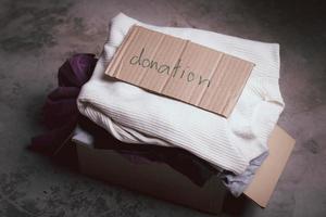 concepto de donación. caja de donación con ropa de donación sobre fondo gris. foto