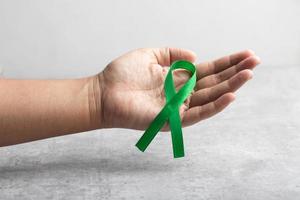Hand holding a green ribbon. Cancer treatment concept. photo