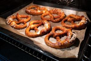 los pretzels horneados con la adición de sal gruesa se encuentran en una bandeja para hornear en el horno. comida tradicional alemana. Oktoberfest. foto