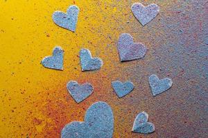 Valentine's Day. Many hearts symbol of love sprinkled with multicolored bright powder, on a yellow background. Romantic concept. photo