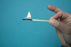 Burning match. Flame on the head and matchstick, on a blue background. photo