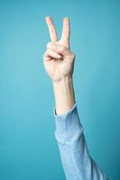 Victory sign, two fingers up, on a blue background. photo