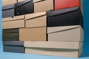 Shoe boxes stacked in a pile, on a blue background. Copy space. Shopping concept. photo