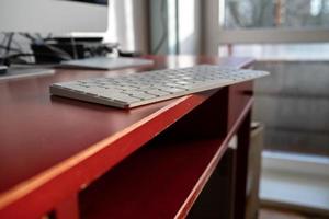 Keyboard is left carelessly on the edge of the desktop and may fall over. Nonchalance attitude to gadgets. photo