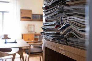 Paper notebooks used and stacked on a rack shelf, cozy office. photo