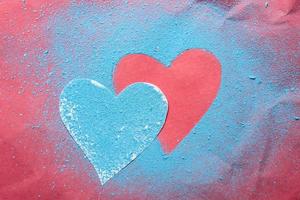 Valentine's Day. Two hearts are a symbol of love, one sprinkled with bright blue powder and the other on a red textured background. photo