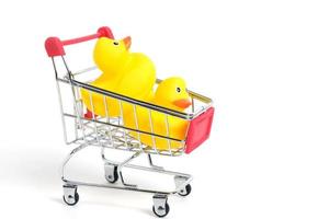 Yellow rubber ducks in shopping cart on a white background.Children goods and purchases.