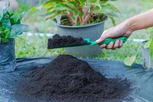 Preparation of soil mixture from fertile compost, humus and vermiculite on  black garbage bag floor in garden. Mixing the soil components for the preparation of the substrate for transplanting plants. photo