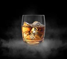 vaso de whisky anidado sobre fondo oscuro con vapor frío y fondo de estudio oscuro. renderizado 3d foto