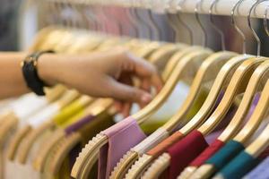 Clothes that are arranged on shelves and hangers photo