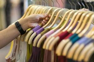 Clothes that are arranged on shelves and hangers photo